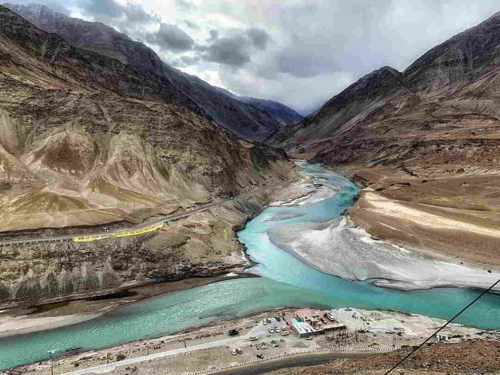 Sangam Point in Ladakh showing the confluence of the Zanskar and Indus rivers surrounded by dramatic Himalayan landscapes.